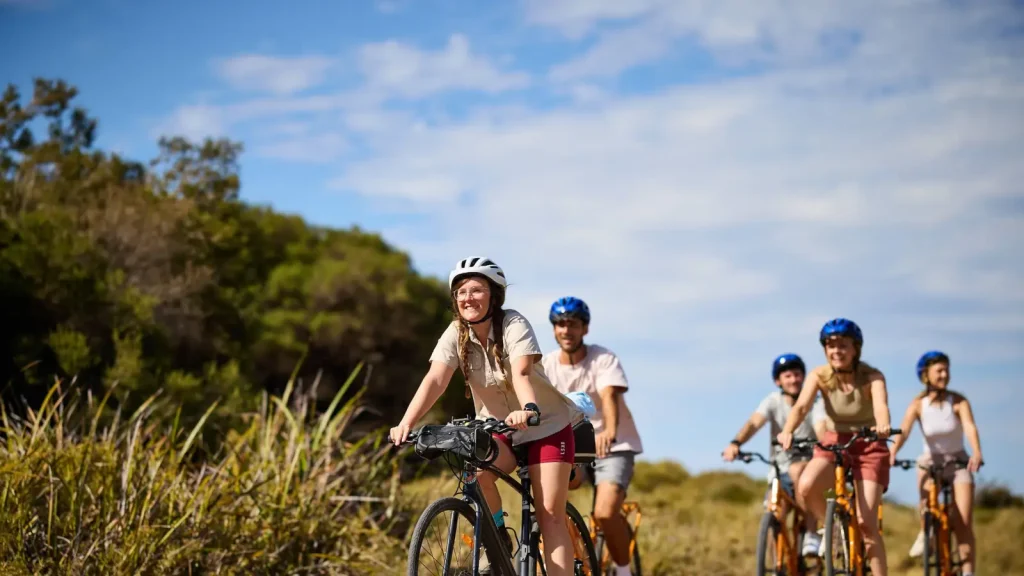 Cyclists riding through coastal scrub on a guided Rottnest Island bike tour
